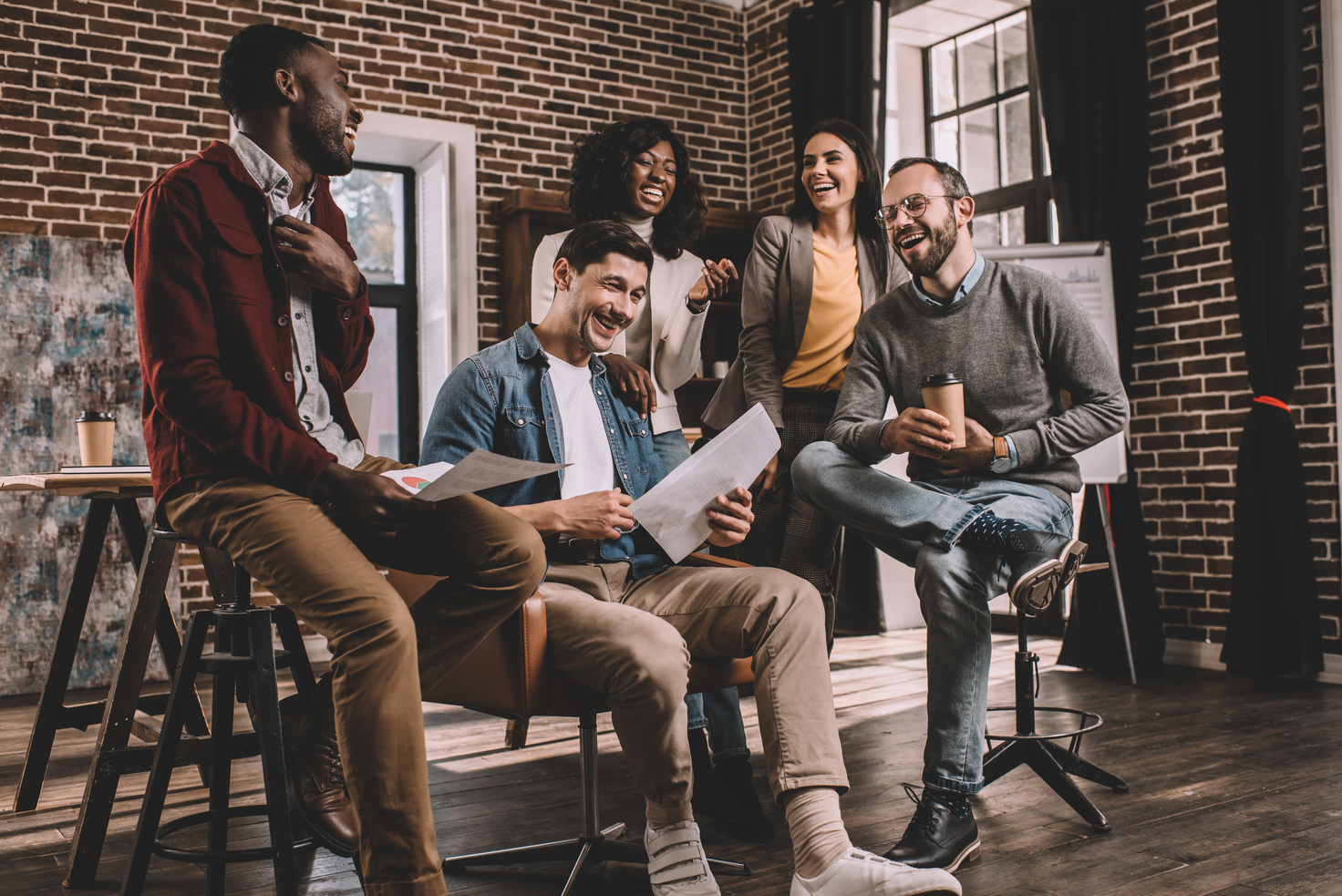 multiethnic group of colworkers smiling and discussing together new project in modern loft office